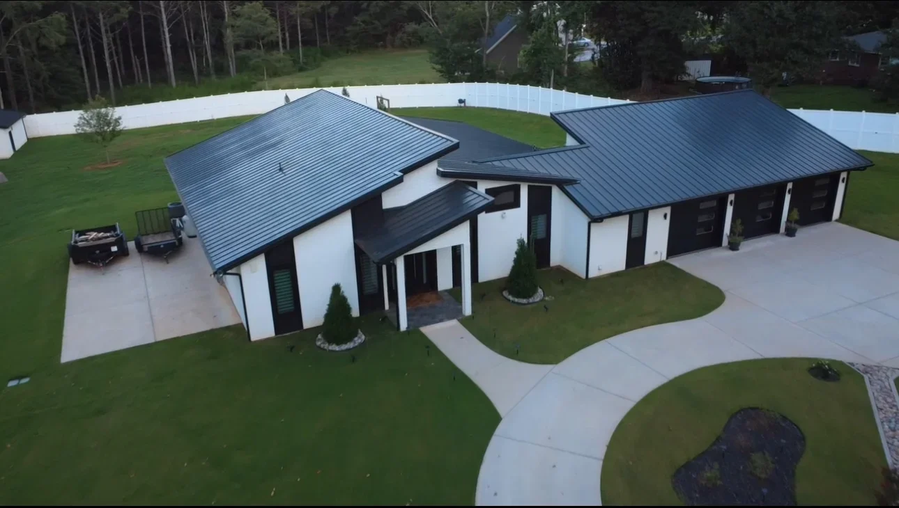 Dark blue metal standing seam roof on white modern home with multiple roof planes and integrated guttering