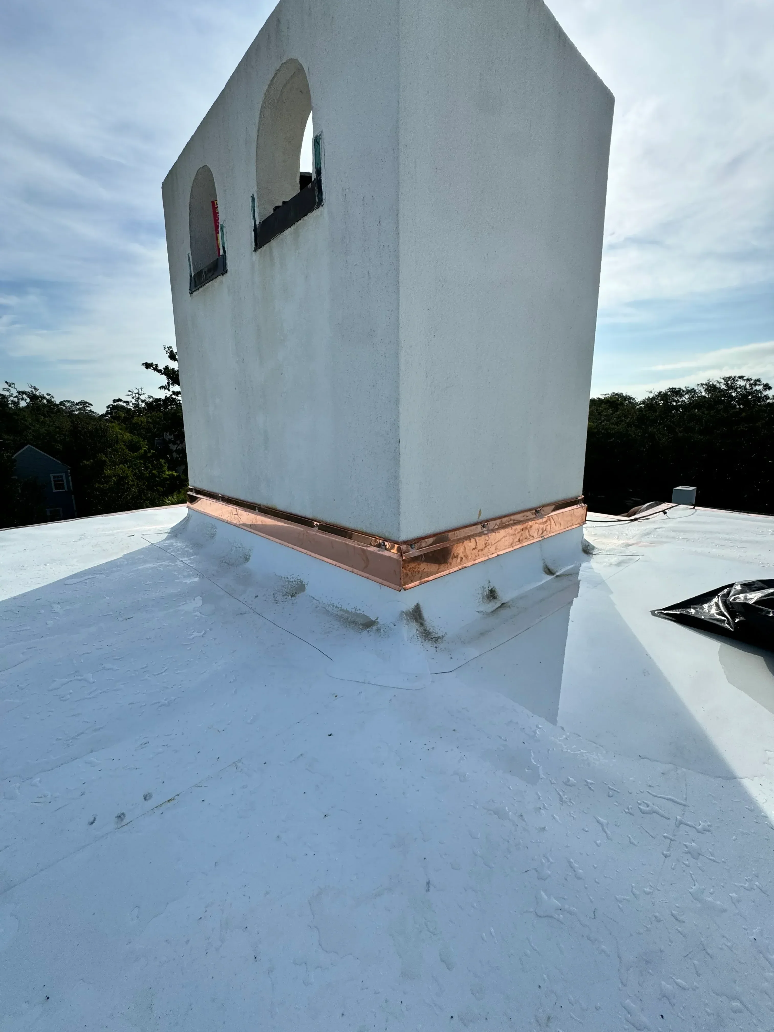 Copper gutter and downspout installed on white fascia board along roofline