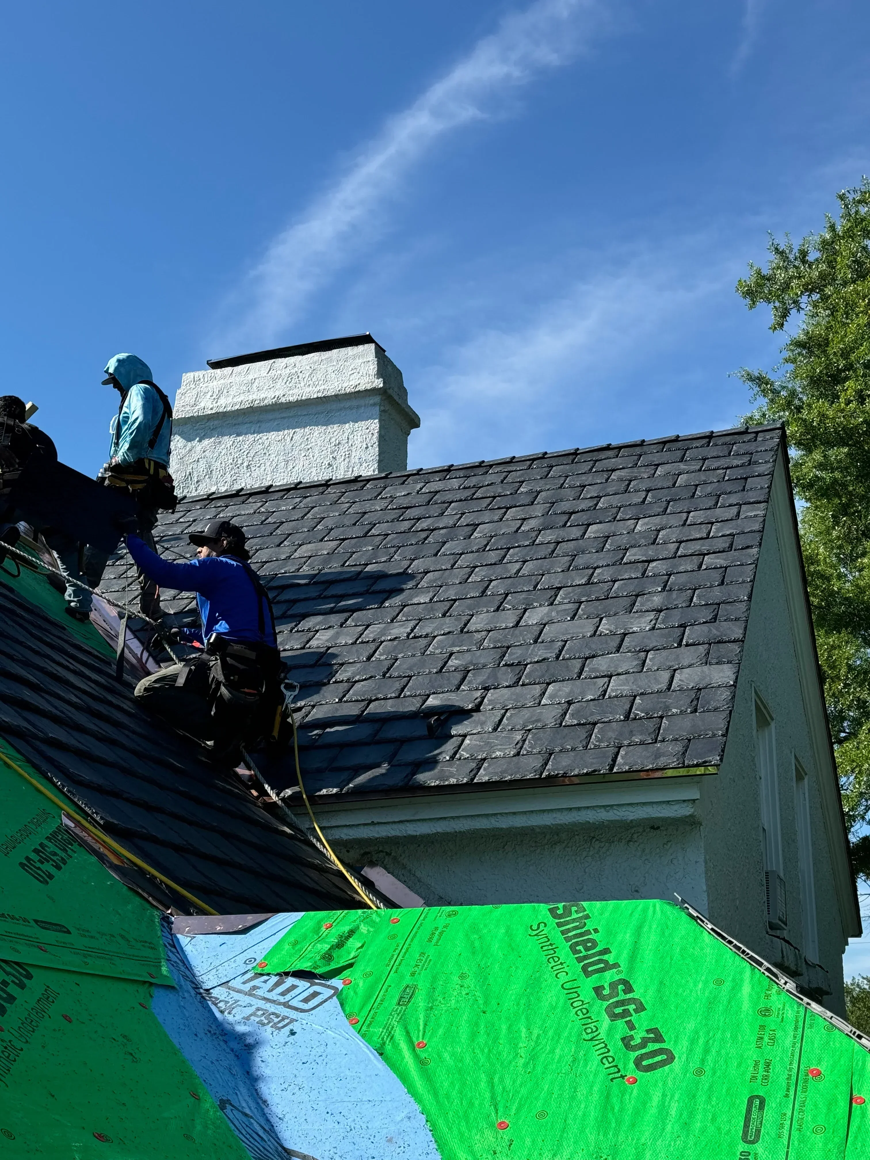 Charcoal architectural shingles installed over green synthetic underlayment on pitched roof