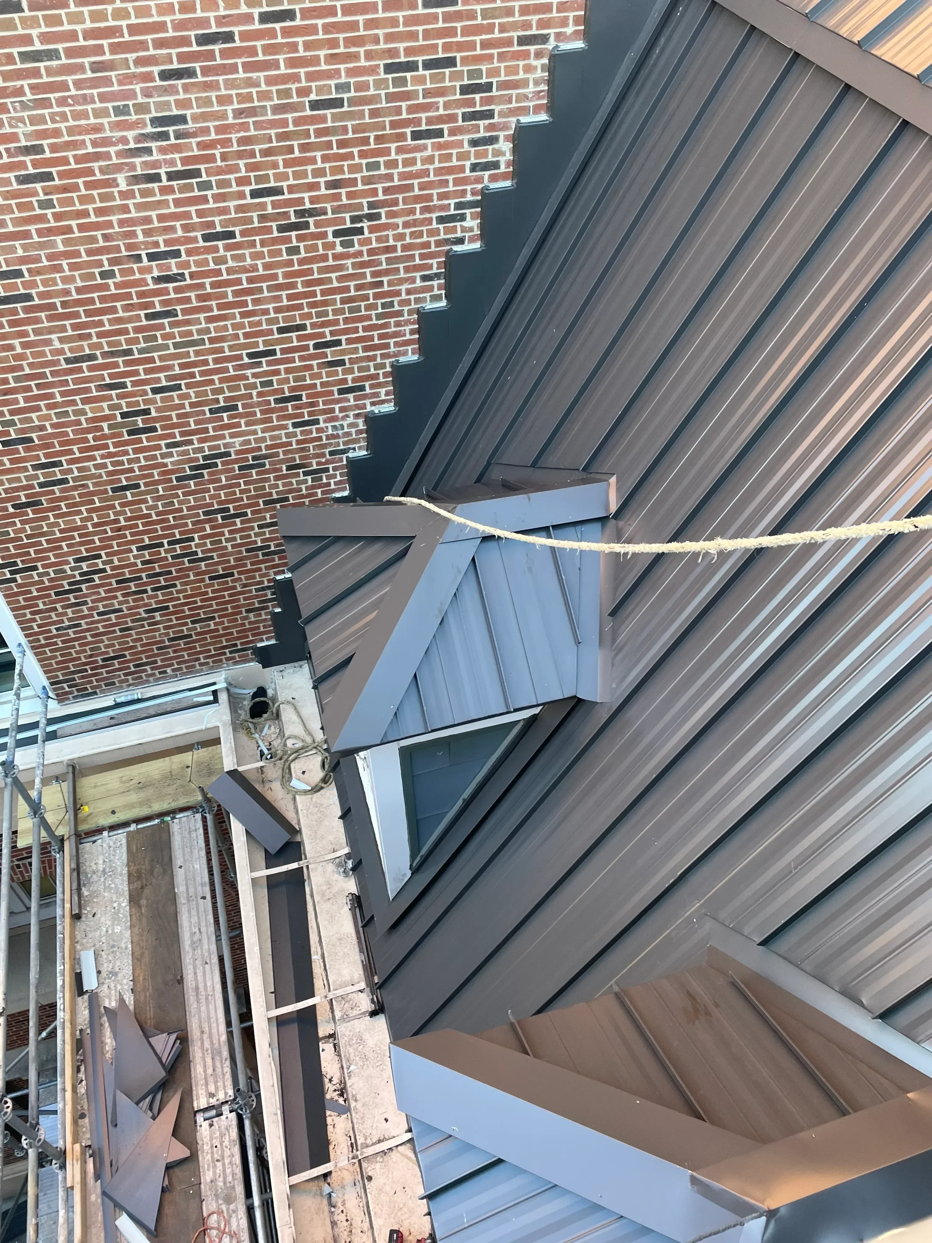 Gray standing seam metal roof with skylight opening and flashing installation