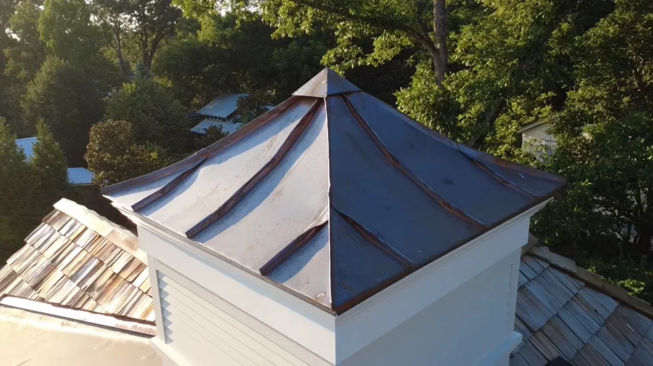 Standing seam metal cupola with navy and white panels on residential roof