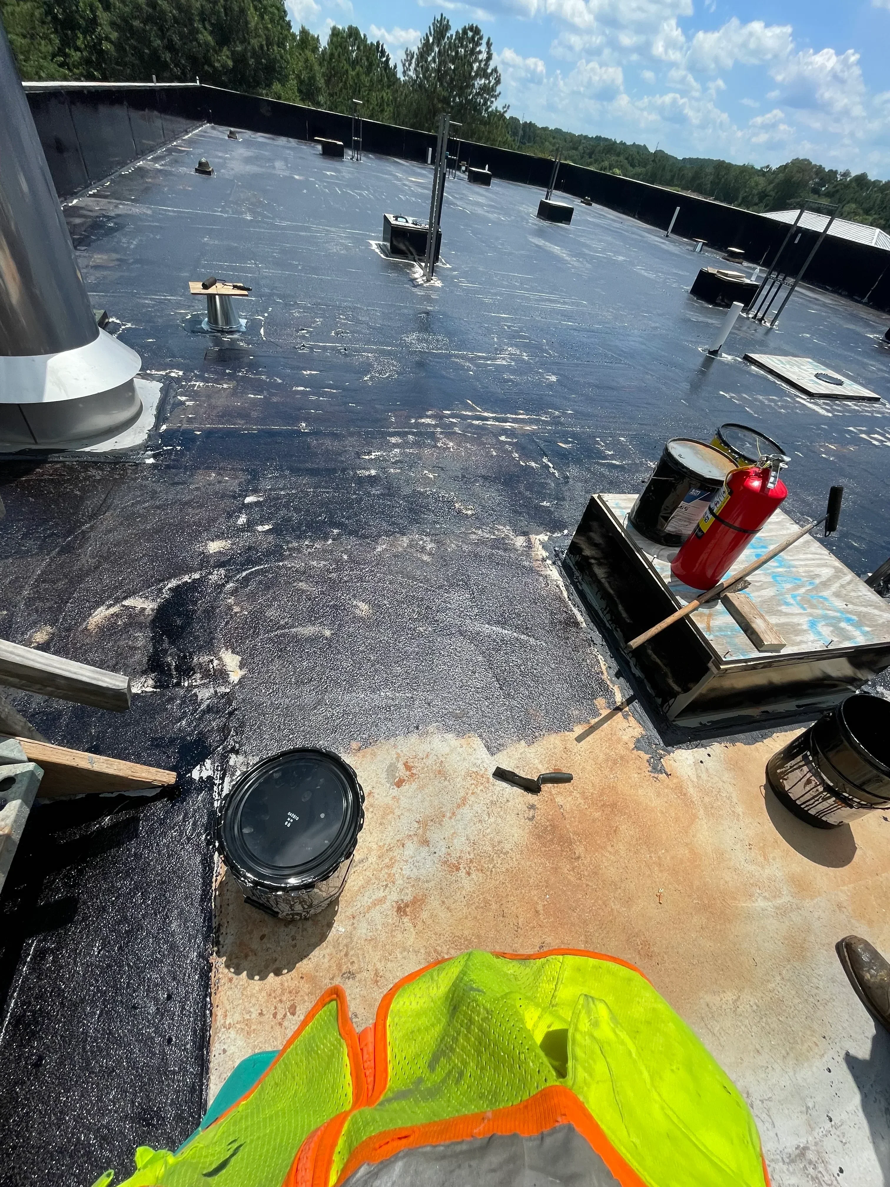 Roof tear-off with exposed decking, staged materials, and debris removal in progress