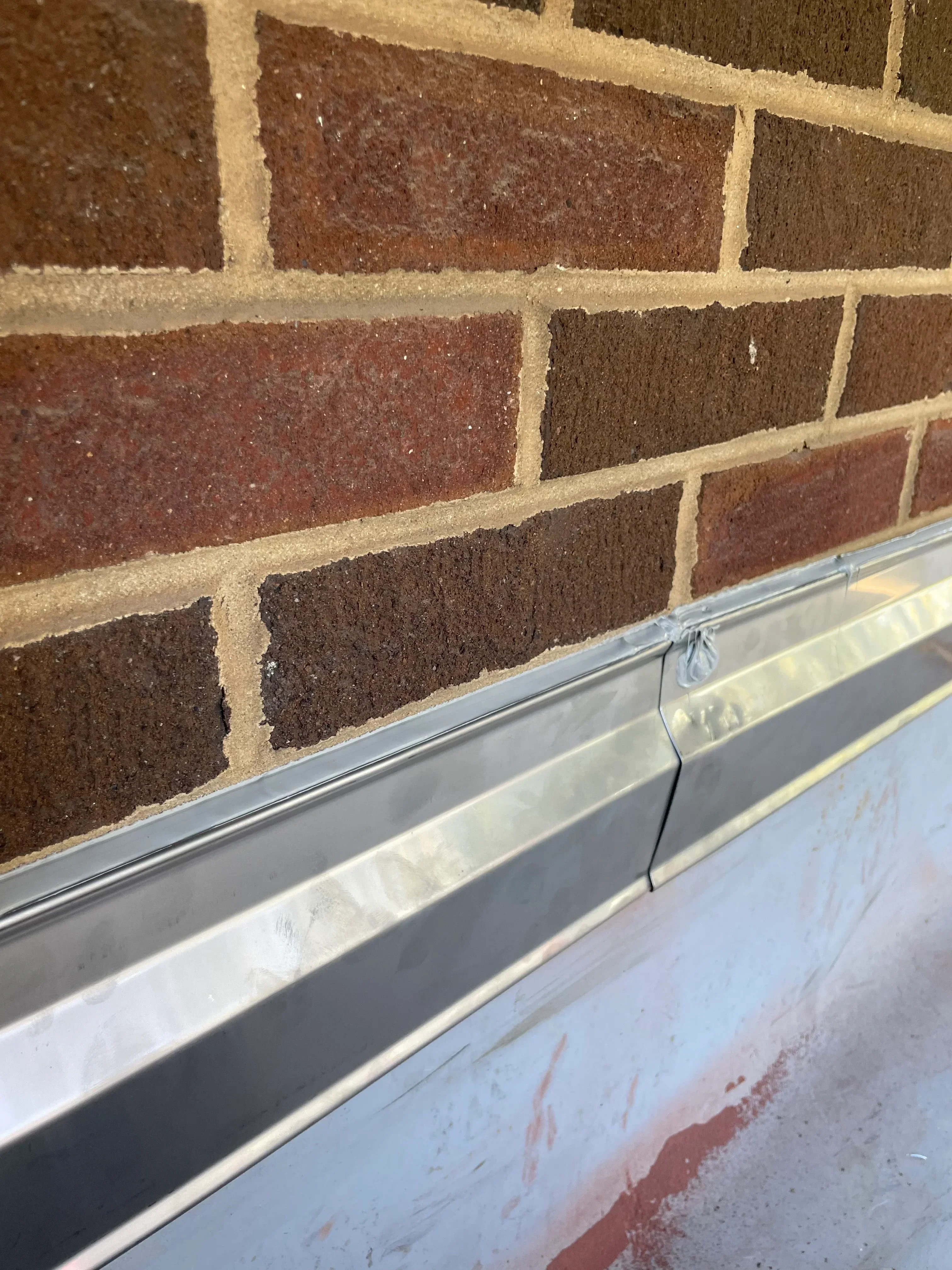 Architectural shingles in brown and red tones with metal flashing and drip edge detail
