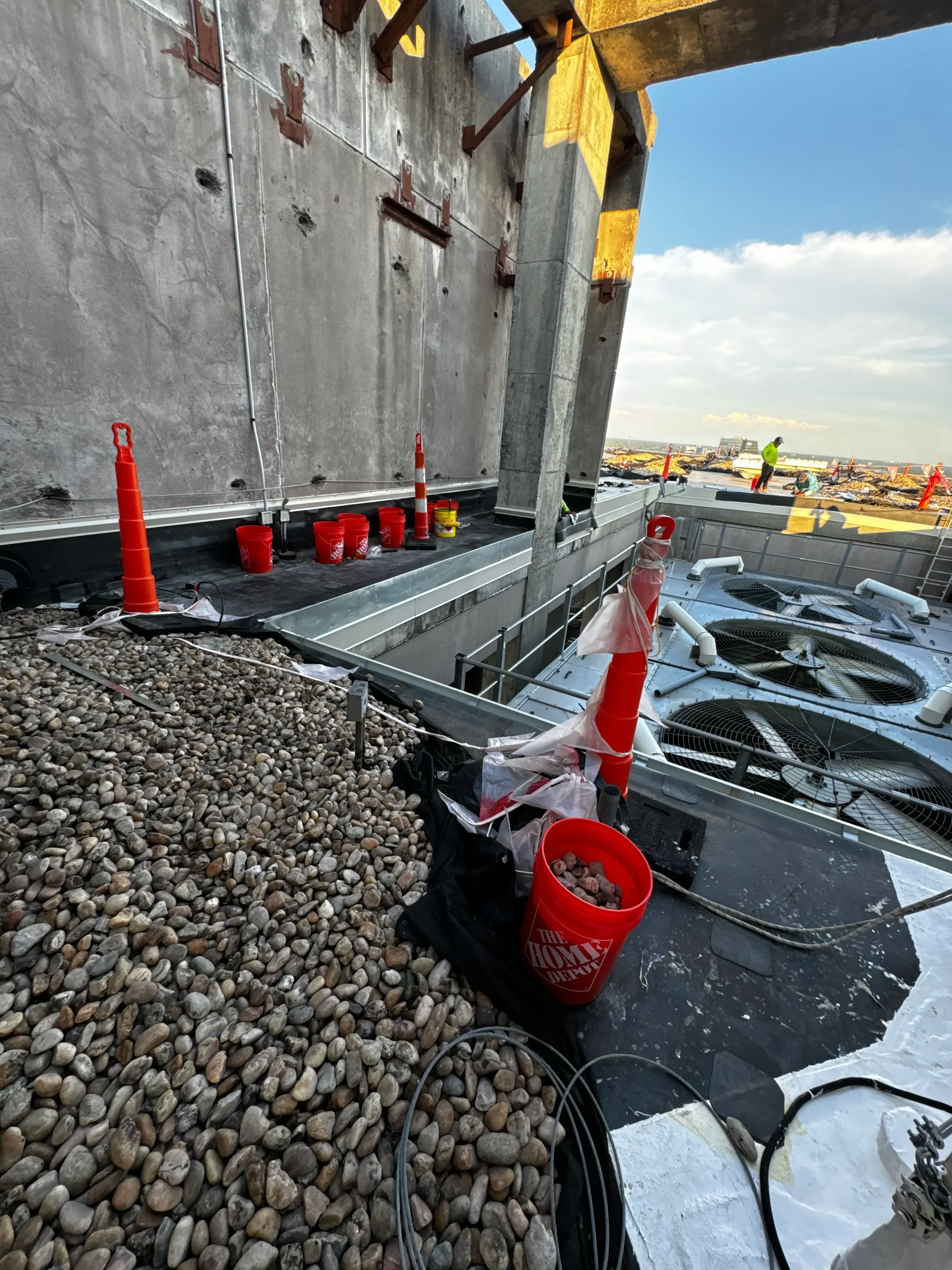 Roofing materials including aggregate stone and equipment staged on commercial roof deck
